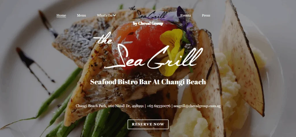 Homepage banner for The Sea Grill Seafood Bistro Bar at Changi Beach, showing a gourmet plated fish dish served with asparagus, mashed potatoes, and root vegetable chips. The text overlay displays menu navigation options, location address, phone number, email, and a button to reserve a table.