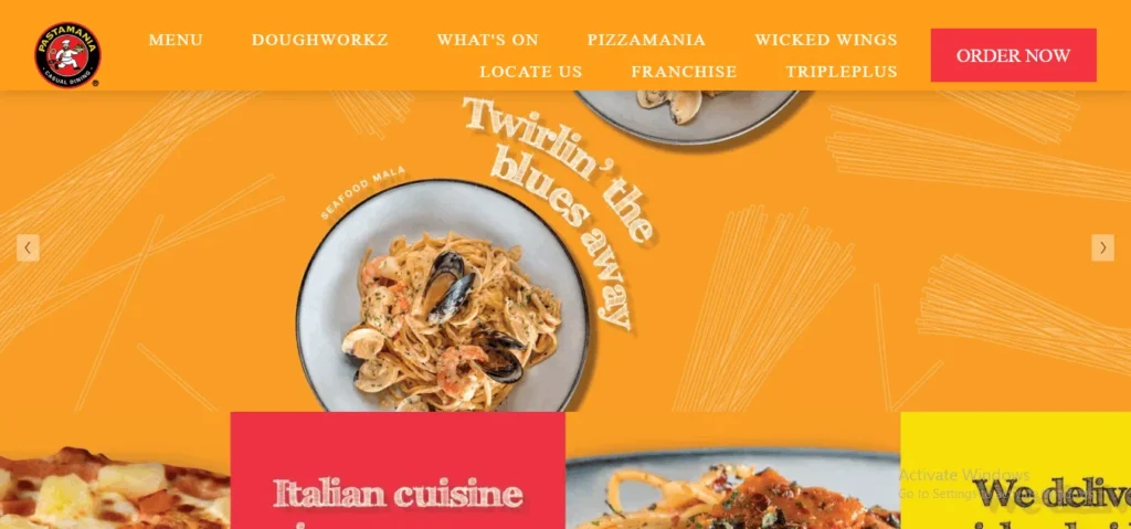 Screenshot of the PastaMania website homepage featuring an orange theme, the PastaMania logo, navigation links, and a prominent banner showing a plate of seafood pasta alongside the text "Twirlin' the blues away."
