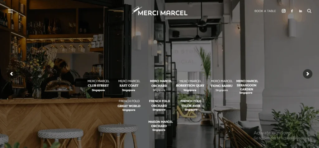 Website homepage for Merci Marcel cafe showing a stylish restaurant interior with a list of Singapore location names overlaying the image.