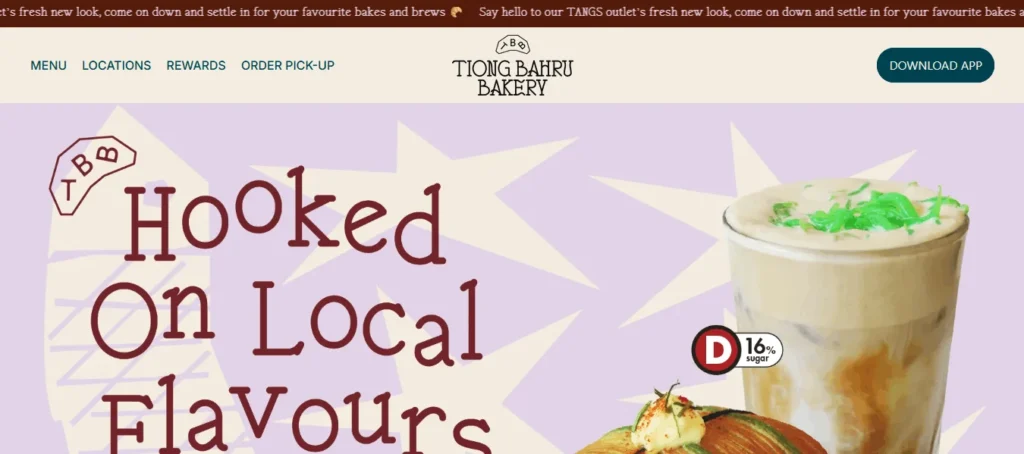 Homepage hero section for Tiong Bahru Bakery showing a navigation bar with links for Menu, Locations, Rewards, Order Pick-Up, and Download App. The banner features the text "Hooked On Local Flavours" set against a lavender starburst pattern with a iced local specialty drink displaying a Grade D sugar rating badge.