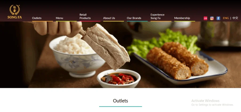 A website header for Song Fa Bak Kut Teh featuring a hand dipping a pork rib into a small bowl of dark soy sauce with red chilies. In the background, a bowl of white rice and a plate of fried ngoh hiang (meat rolls) are displayed alongside the website's navigation menu.