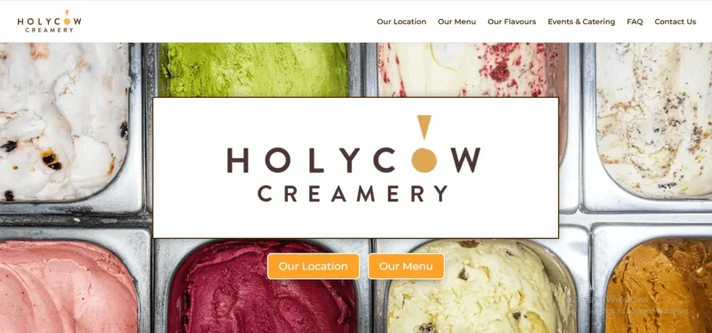 Screenshot of the Holy Cow Creamery website homepage, displaying their central brand logo overlaying metal tubs of assorted colorful ice cream flavors, with navigation buttons for "Our Location" and "Our Menu."