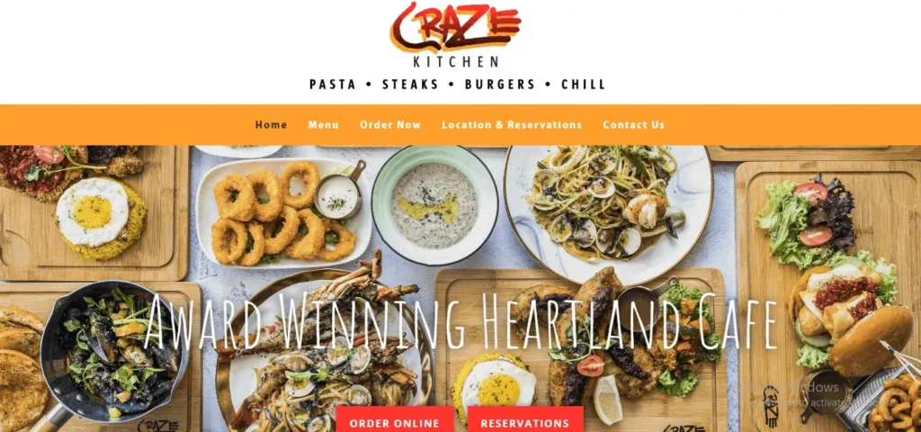 Screenshot of the Craze Kitchen website homepage, featuring the brand logo with the subtitle "Pasta • Steaks • Burgers • Chill" and a vibrant banner showing an assortment of Western and fusion dishes, including seafood pasta, burgers, calamari, and rice dishes, with a text overlay reading "Award Winning Heartland Cafe."