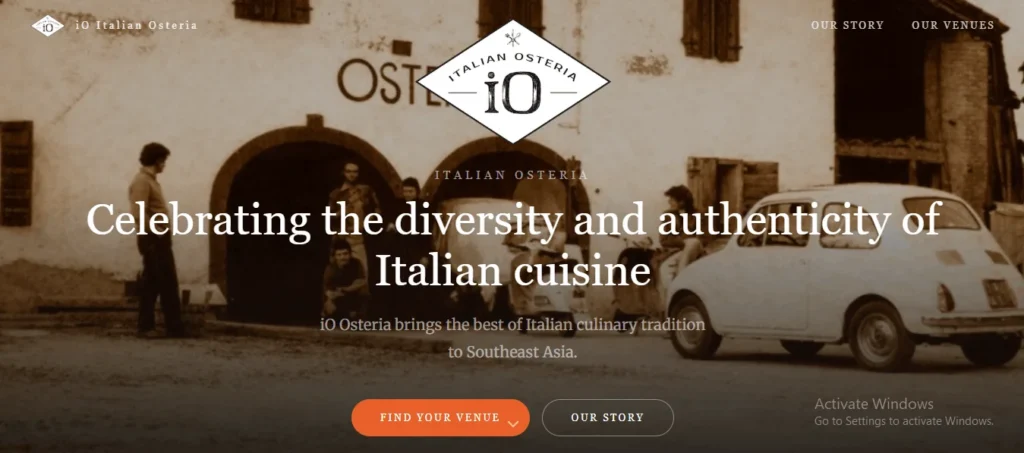 A screenshot of the homepage hero banner for iO Italian Osteria. The background shows a vintage, sepia-toned photograph of people standing outside a rustic Italian building next to a classic white Fiat car and a scooter. Overlay text reads "Celebrating the diversity and authenticity of Italian cuisine" alongside action buttons for "Find Your Venue" and "Our Story."