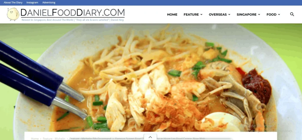 Screenshot of the DanielFoodDiary.com website showing a close-up banner image of a Singaporean laksa dish topped with shredded chicken, bean sprouts, prawns, crab, and chili paste, with blue chopsticks resting in the bowl.