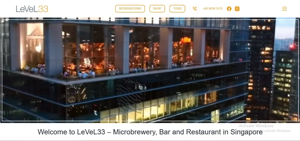 LeVeL33 website homepage showing an exterior rooftop view of the illuminated microbrewery, bar, and restaurant overlooking the Singapore skyline at night.