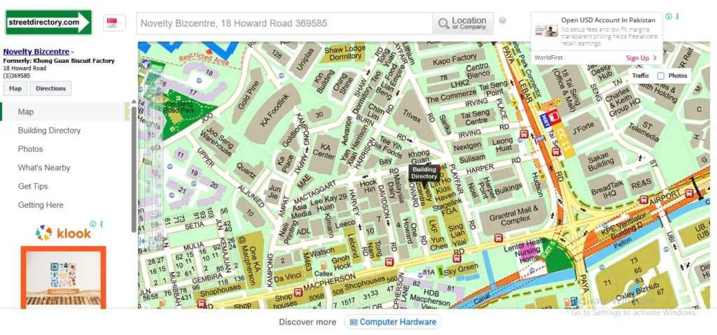 A screenshot of a street map interface on StreetDirectory.com showing the location of Novelty Bizcentre at 18 Howard Road, formerly Khong Guan Biscuit Factory. A location pin marks the building among surrounding roads and industrial developments near the Tai Seng MRT station and Paya Lebar Park Connector.