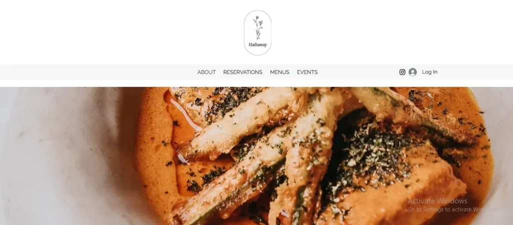 Screenshot of the Hathaway restaurant website header featuring a minimalist white layout with a central oval logo showing a floral illustration and the text "Hathaway." Below the logo, a navigation bar includes options for "ABOUT," "RESERVATIONS," "MENUS," and "EVENTS," alongside social icons and a "Log In" link. Beneath the header, a cropped hero image shows a dish served in a light-colored bowl, featuring curry sauce topped with tempura-battered vegetables sprinkled with herbs.