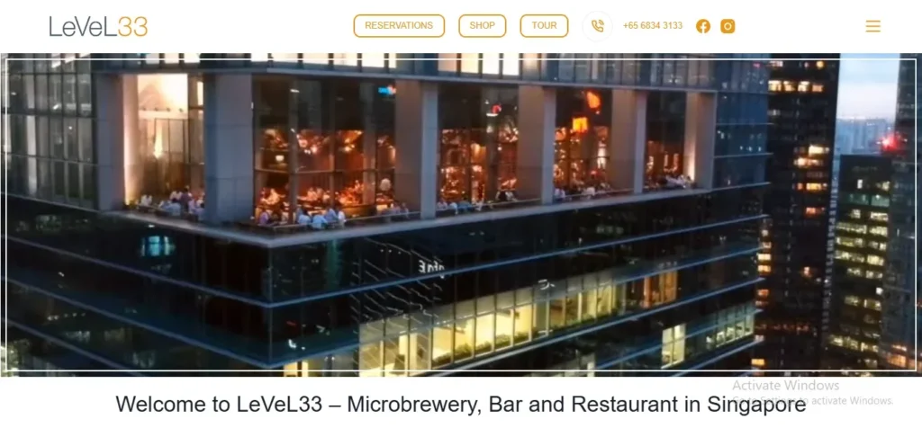 Website banner for LeVeL33 showing an exterior view of a high-rise rooftop restaurant and microbrewery at night with guests dining on an outdoor terrace overlooking the city.