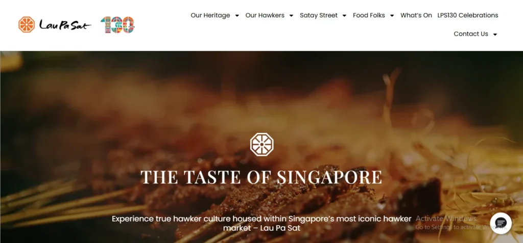 Screenshot of the Lau Pa Sat website hero banner featuring a warm, close-up background of grilled satay skewers with the overlay text "THE TASTE OF SINGAPORE" and a caption reading "Experience true hawker culture housed within Singapore's most iconic hawker market – Lau Pa Sat." Top navigation links include "Our Heritage," "Our Hawkers," "Satay Street," and "Food Folks."