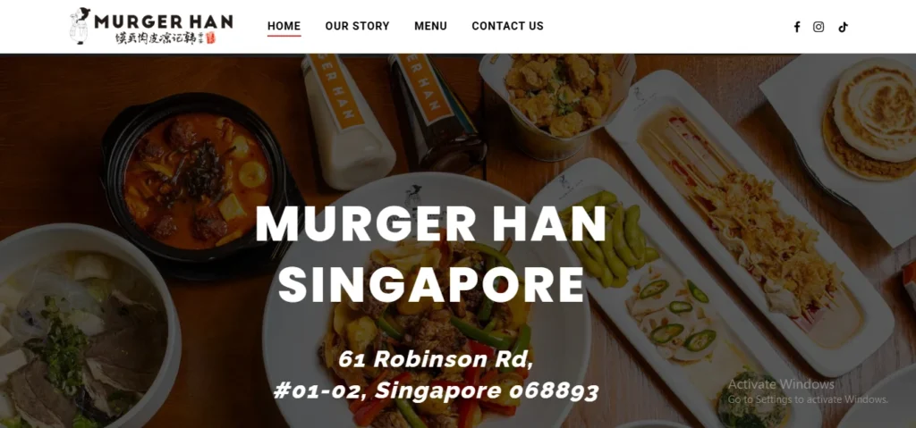 Website homepage header for Murger Han Singapore featuring a flat-lay view of Shaanxi cuisine dishes including noodle soups, stir-fried biang biang noodles, Chinese burgers (murger), and side dishes on a dark wooden table, with text overlaid reading "MURGER HAN SINGAPORE" along with the address "61 Robinson Rd, #01-02, Singapore 068893".